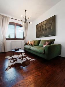 a living room with a green couch and a table at TatryView Apartments by KingDubaj in Veľká Lomnica