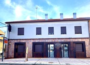 un bâtiment blanc avec des portes brunes dans une rue dans l'établissement Apartamentos Puertas del Orbigo, à Carrizo de la Ribera