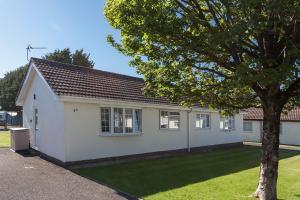 a white house with a tree in front of it at 46 Gower Holiday Village in Swansea