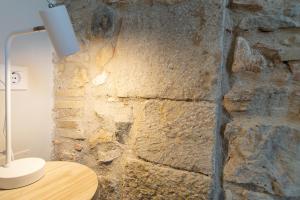 - un mur en pierre dans une pièce avec une table et une lampe dans l'établissement Caelus Boutique Studio, à Gérone