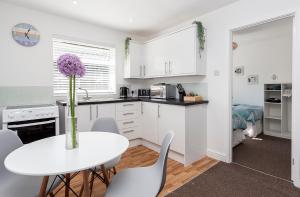 a white kitchen with a white table and chairs at 46 Gower Holiday Village in Swansea
