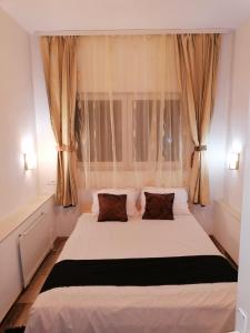 a bedroom with a large white bed in front of a window at Excellency apartmani in Banja Luka