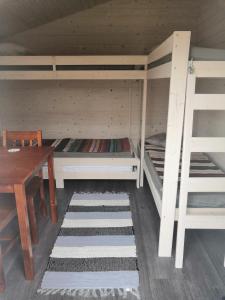 a room with two bunk beds and a wooden table at Mäentaustan aitat in Janakkala