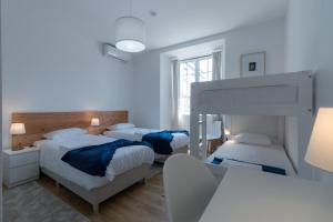 a white bedroom with two beds and a table at Lagoa Hostel & Suites in Lagoa