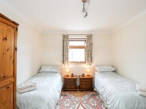 two twin beds in a room with a window at Penrallt Fawr in Caernarfon