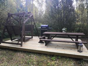 a picnic table and a bench on a wooden deck at Mäentaustan aitat in Janakkala