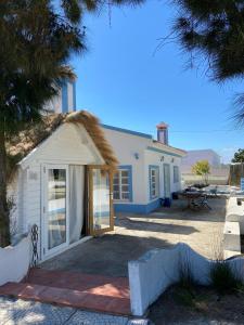 uma pequena casa branca com telhado de palha em Casa Paloma em Comporta