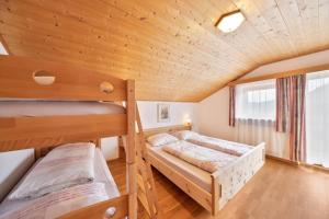 two bunk beds in a room with a wooden ceiling at Wieserhof Ferienwohnung Zirm in Sarntal