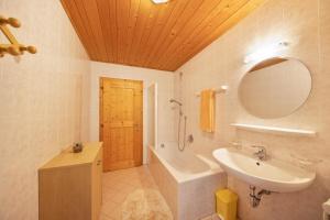 a bathroom with a sink and a tub and a mirror at Wieserhof Ferienwohnung Zirm in Sarntal