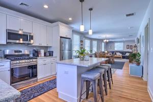 a kitchen with white cabinets and a island with bar stools at New London Hideaway Near Beaches and Local Spots! in New London