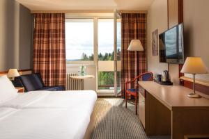 ハルラホフにあるOREA Resort Sklář Harrachovのベッドと大きな窓が備わるホテルルームです。