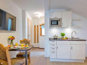 eine Küche mit weißen Schränken und einem Tisch mit Essen drauf in der Unterkunft Gäste- und Appartementhaus Stachl in Waging am See