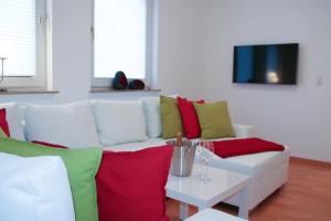 a living room with a white couch with red and green pillows at Premium Ferienwohnung Sonnenaufgang in Witzenhausen