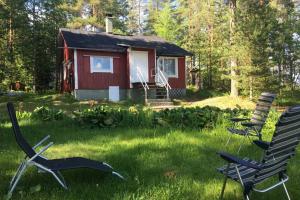 una cabaña en el bosque con sillas en el patio en Cotteg Marjakallio (BerryRock), en Punkaharju