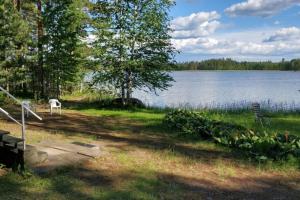 a view of a lake with a bench and a chair at Cotteg Marjakallio (BerryRock) in Punkaharju +11 photos
