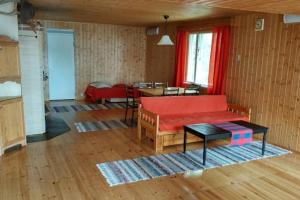ein Wohnzimmer mit einem roten Sofa und einem Tisch in der Unterkunft Cotteg Marjakallio (BerryRock) in Punkaharju