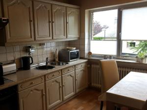 a kitchen with white cabinets and a sink and a microwave at Ferienwohnungen am Finkenweg in Bestwig