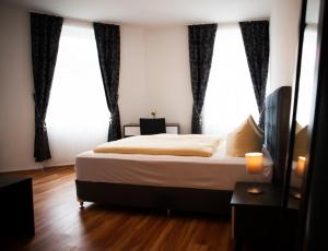 a bedroom with a bed and two large windows at Wiesentäler Hof Hotel garni in Konstanz
