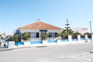 a white house with a blue and white fence at West Coast Surf Hostel in Areia Branca