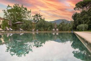 een zwembad met stoelen en parasols en een zonsondergang bij Hotel Villa San Michele in Lucca