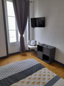a living room with a flat screen tv and a chair at Le Samwest in Arromanches-les-Bains