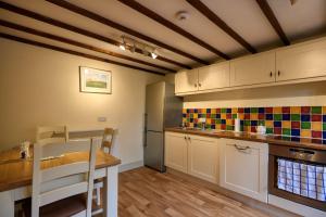cocina con armarios blancos y mesa de madera en Fab 2 Bed Cotswolds Cottage with Private Courtyard, 