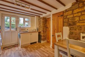 a kitchen with a table and a stone wall at Fab 2 Bed Cotswolds Cottage with Private Courtyard 