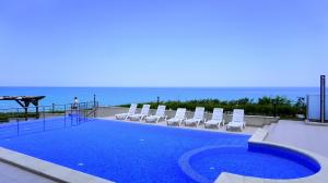 a swimming pool with chairs and the ocean in the background at Бяла Клиф Форест - Byala Cliff Forest in Byala