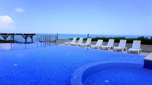 a swimming pool with chairs and the ocean in the background at Бяла Клиф Форест - Byala Cliff Forest in Byala +7 photos