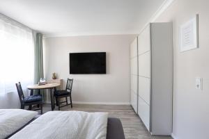 a white bedroom with a table and a tv at S.F.C. Apartments in Trier