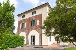 an old brick building with green windows and trees at Hotel Villa San Michele in Lucca