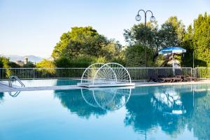 a swimming pool with two chairs and an umbrella at Hotel Villa Maria in Desenzano del Garda