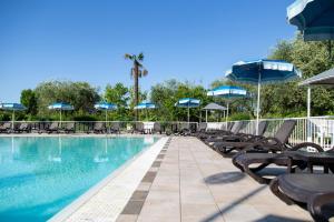 a swimming pool with chairs and umbrellas at Hotel Villa Maria in Desenzano del Garda
