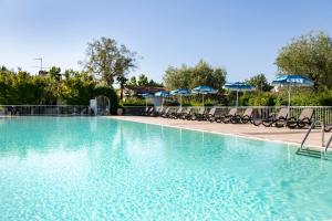 a large swimming pool with chairs and umbrellas at Hotel Villa Maria in Desenzano del Garda