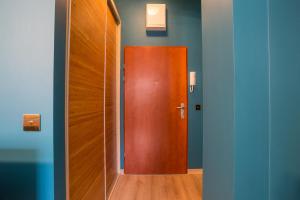 a wooden door in a room with blue walls at Apartament Cichy Zakątek obok fontanny Neptuna in Gdańsk