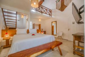 a bedroom with a large white bed with a bench at Pousada Rota Ecológica in Pôrto de Pedras