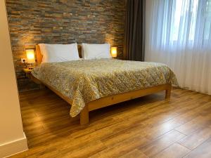 ein Schlafzimmer mit einem Bett und einer Ziegelwand in der Unterkunft Podina Resort Hotel & Spa in Ungureni