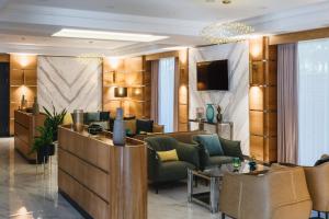 a lobby with couches and chairs and a television at ATECA Hotel Suites Tashkent in Tashkent