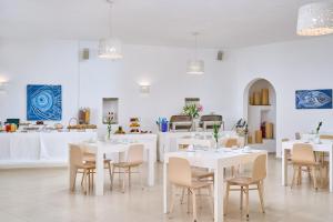 a dining room with white tables and chairs at Paolas Τown Boutique Hotel in Mikonos