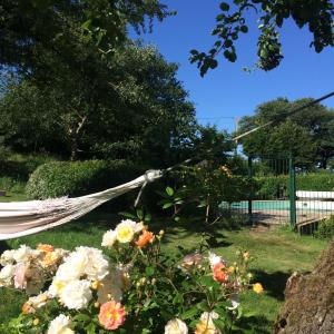 a hammock in a garden with flowers at Tillac Chambres d'hôtes in Pléchâtel