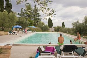 um grupo de pessoas sentadas ao redor de uma piscina em Villa Brignole em Montaperti