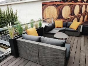 een patio met rieten meubels en een houten terras bij Appartement ' Het Zilte'. in Yerseke