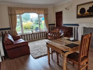 a living room with a wooden table and leather furniture at Mather House Retreat in Wantage