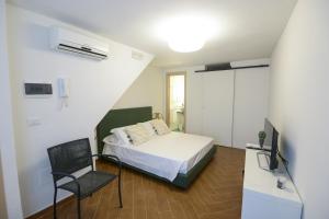 ein Schlafzimmer mit einem Bett, einem Stuhl und einem TV in der Unterkunft San Domenico in Bari