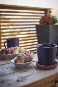 FjordgårdにあるSegla bed & goの木製テーブルの上に2皿のパンとカップ
