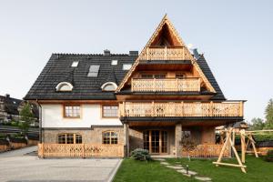 una gran casa de madera con techo de gambrel en Apartamenty Franka Kościelisko, en Kościelisko
