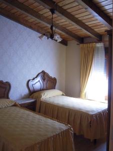 a bedroom with two beds and a window with curtains at Casa Rural Carmina in Berlanga de Duero