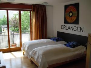 two beds in a hotel room with a balcony at Studio A Am Burgberg in Erlangen +25 photos
