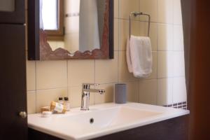 a bathroom with a white sink and a mirror at Andros Melissari in Koumárion