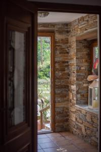 an open door to a room with a stone wall at Andros Melissari in Koumárion